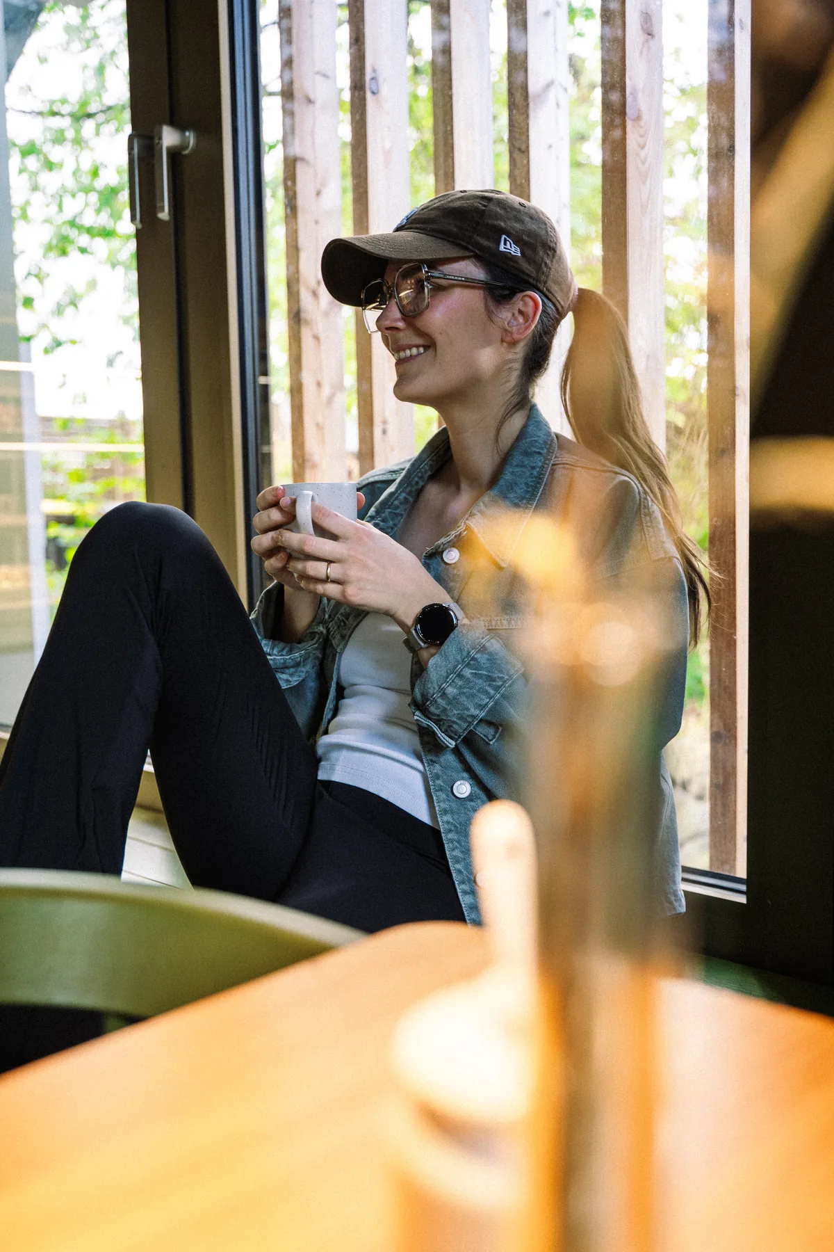 Ein Gast genießt einen Kaffee am sonnigen Fensterplatz im Waldcafé Blattwerk