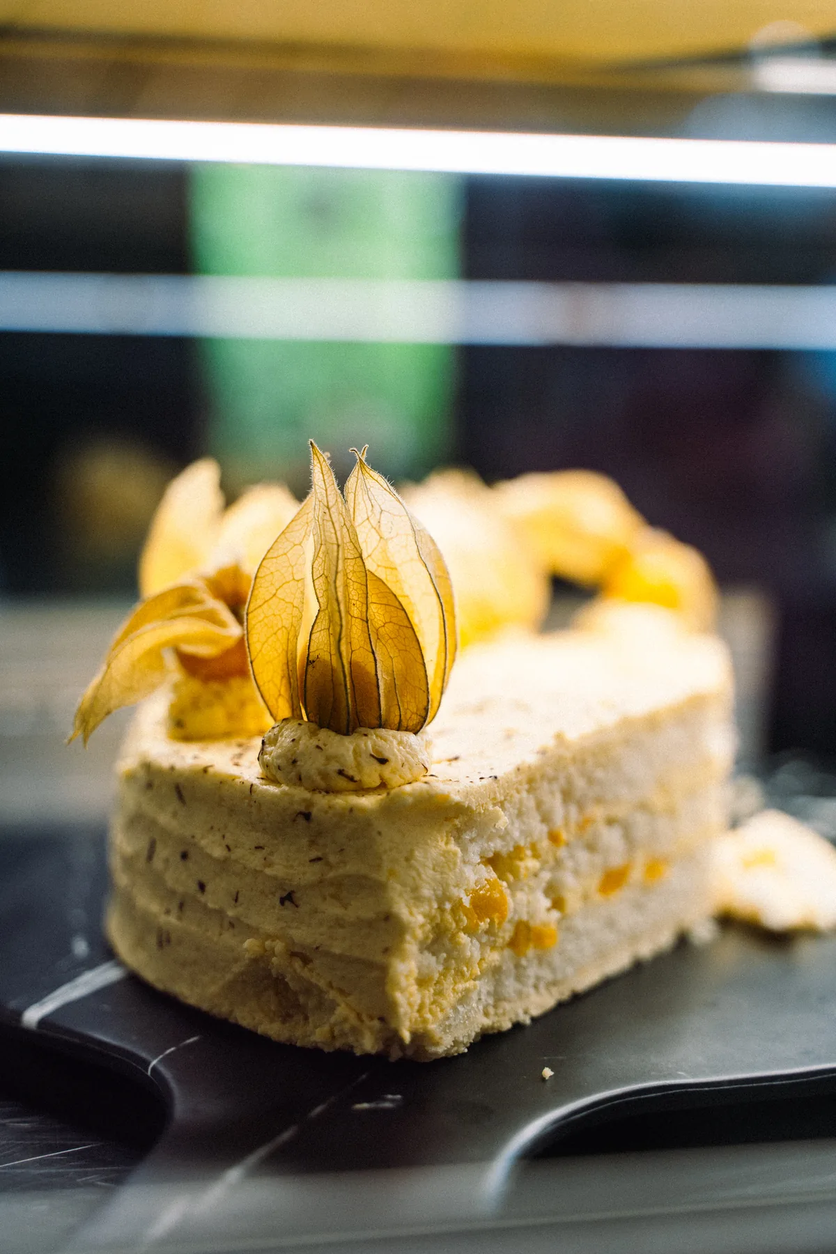 Kuchen mit heller Creme und Physalis in der Kuchentheke des Waldcafés Blattwerk