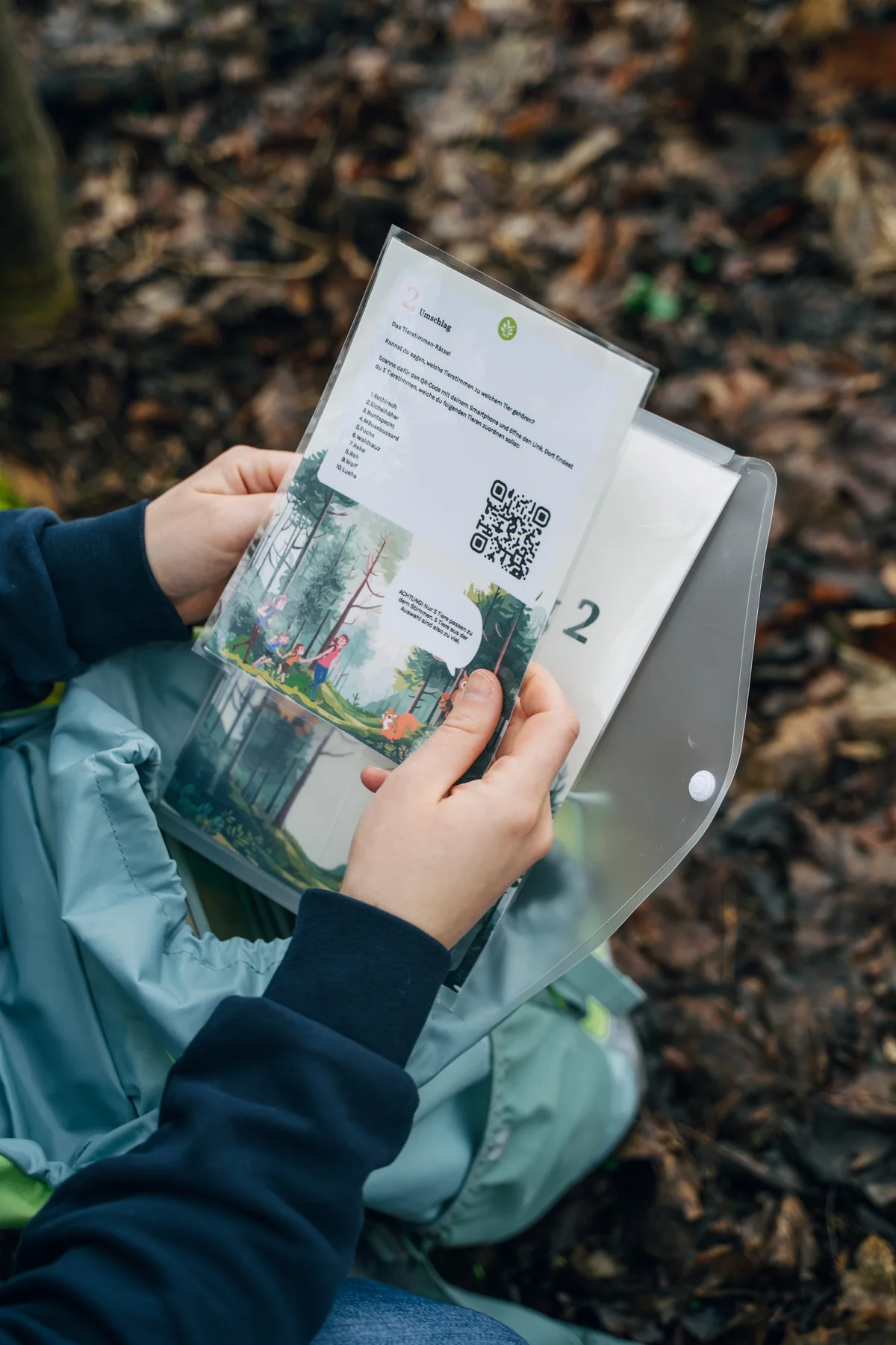 Eine Rätselkarte aus dem Erlebnisrucksack wird im Wald gelesen