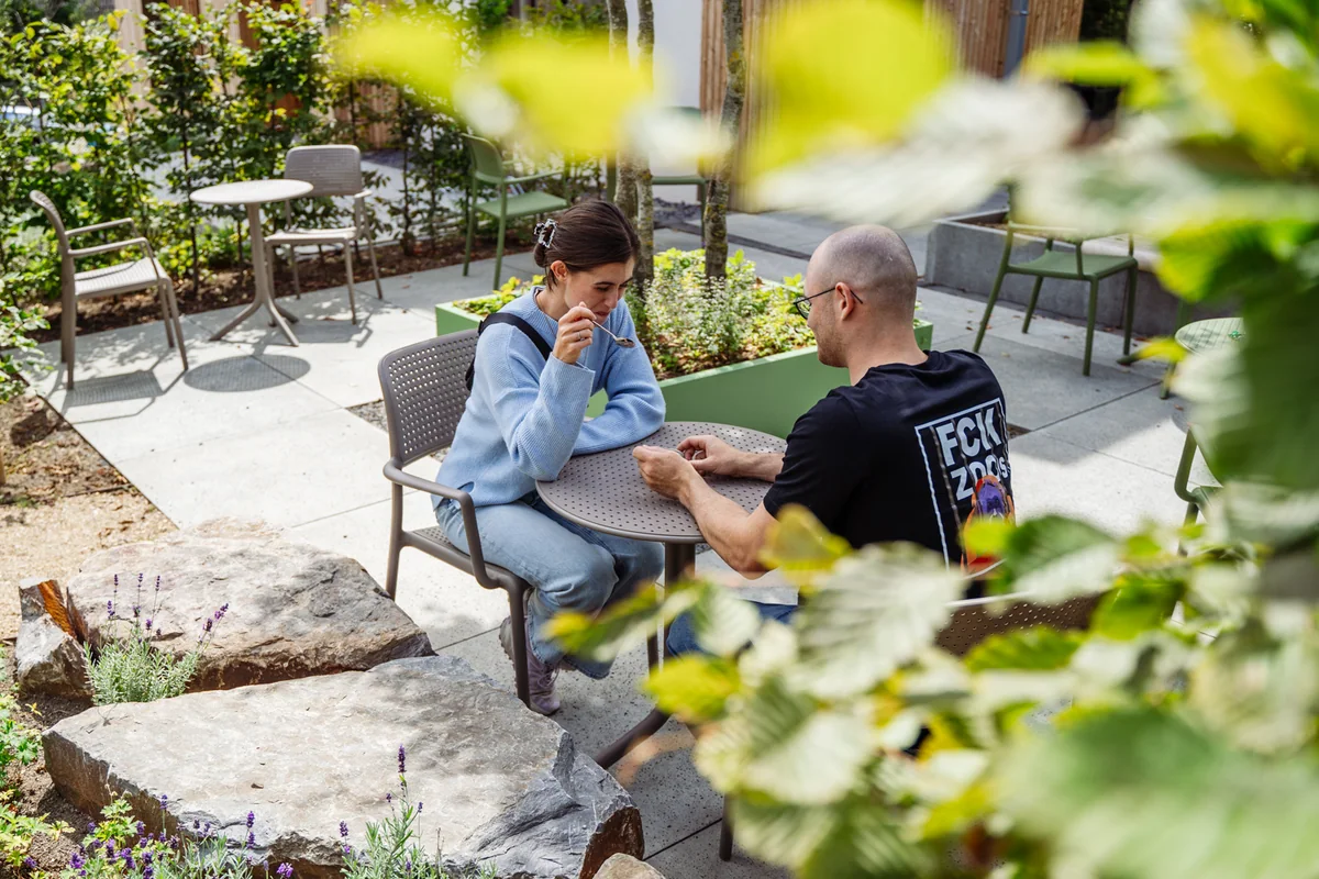 Gäste sitzen zwischen Pflanzen auf der Terrasse des Café Blattwerk